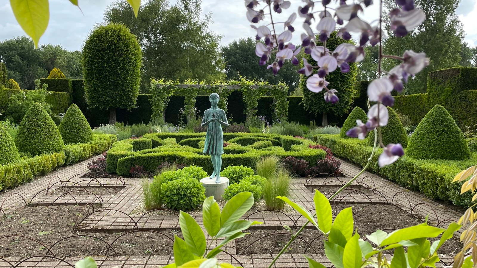Bronze statue of a child in the formal knot garden at Waterperry House