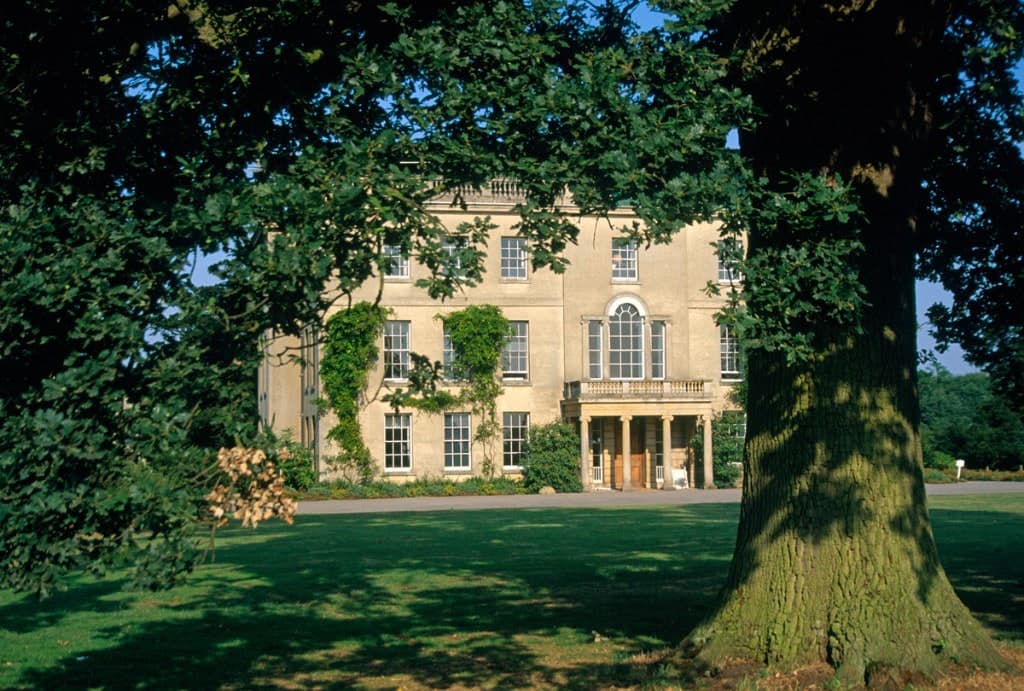Waterperry House's front entrance and portico, framed by mature trees