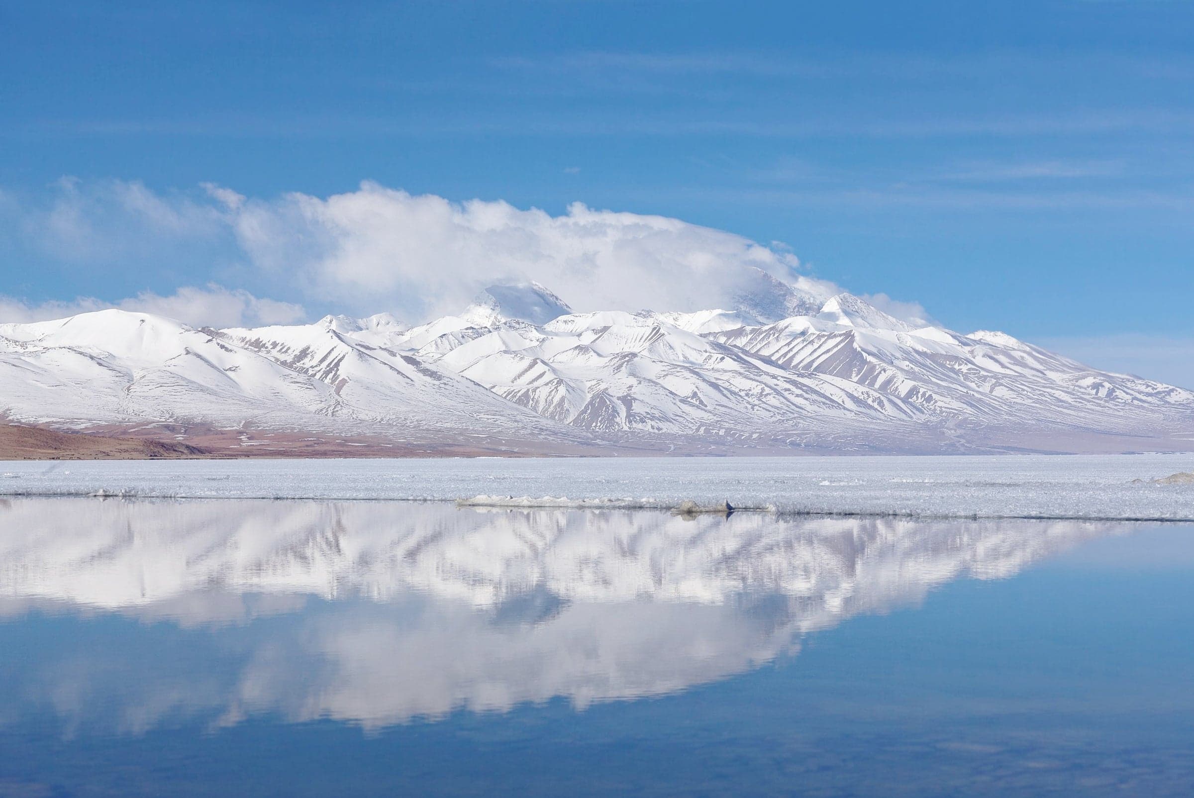 A still mountain lake reflecting snow-covered peaks.