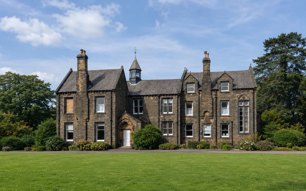 Brinscall Hall, dark millstone grit Victorian manor with Gothic arched porch and cupola, wide lawn and mature trees